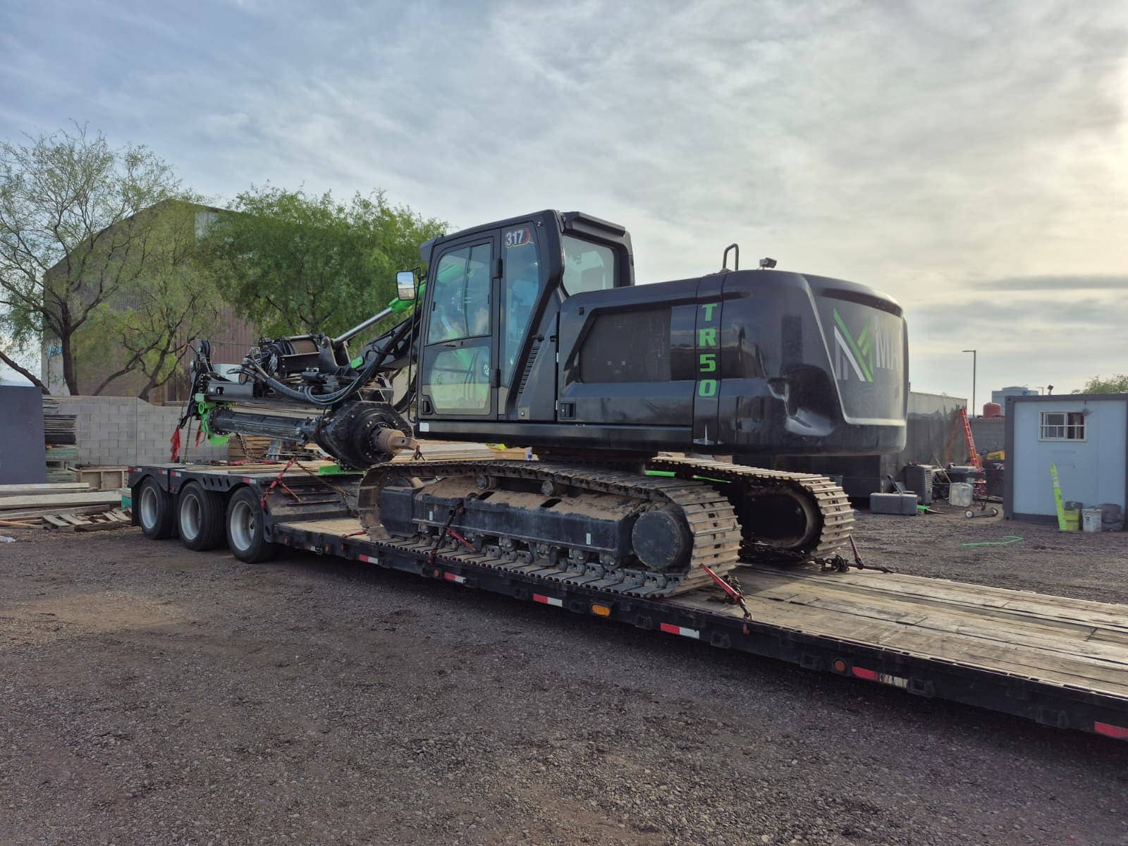 Crawler drill rig loaded on a lowboy trailer at a yard before delivery.