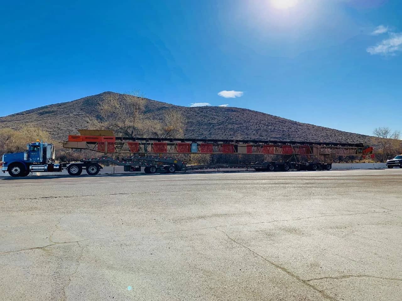 Extendable RGN hauling a belt conveyor over 100 feet long, strapped and chocked.