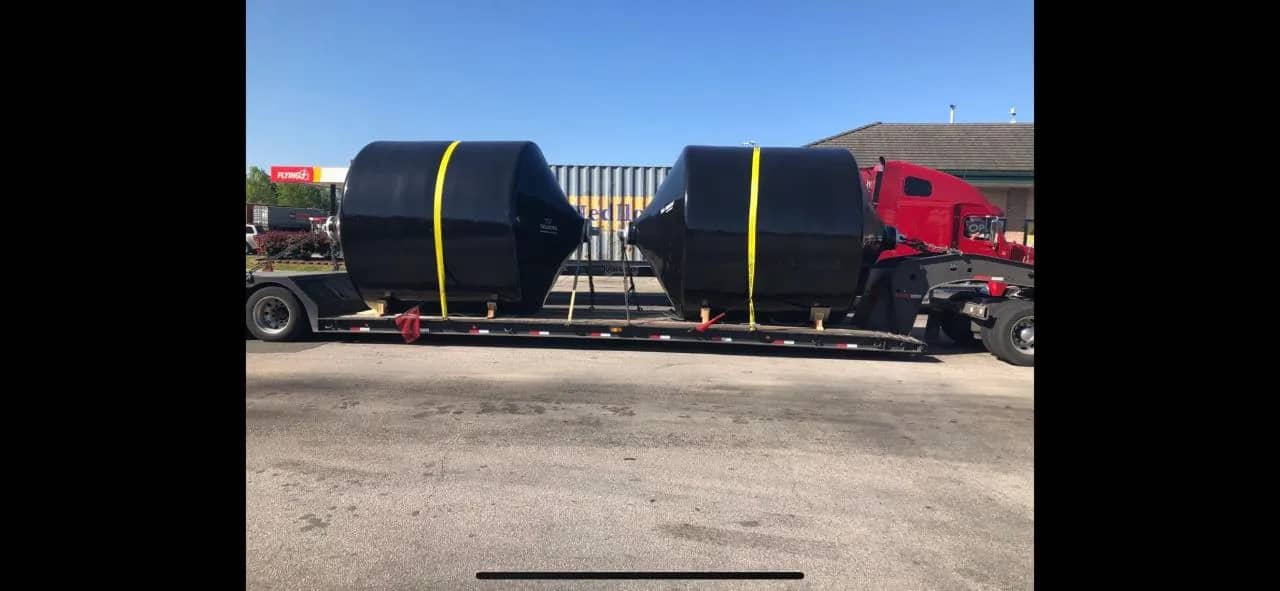 RGN hauling oversized oceanic bumpers staged before departure.