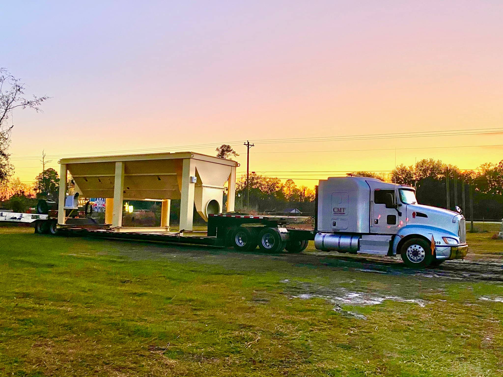Chrome tractor with a double-drop RGN trailer staged for heavy haul.