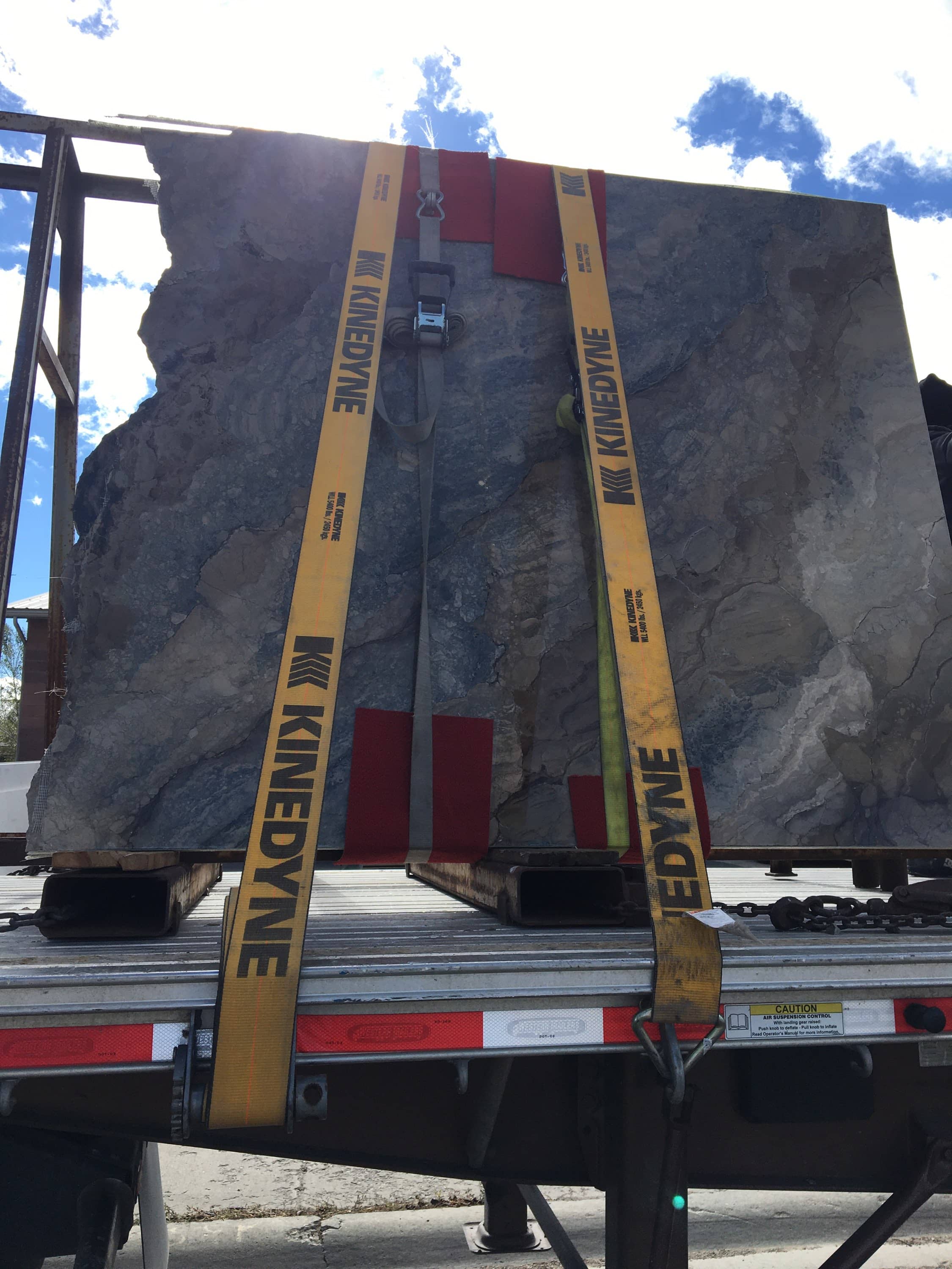 Granite slab strapped upright on a flatbed trailer.
